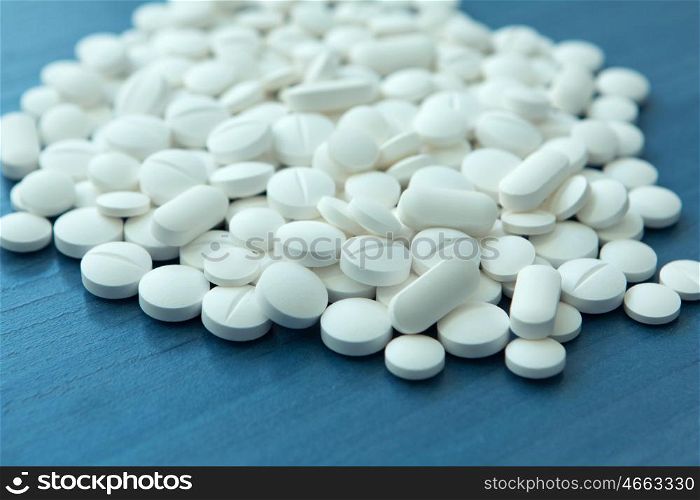 Top view of the Spilled white pills on the blue wooden surface