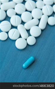 Top view of the Spilled white pills on the blue wooden surface