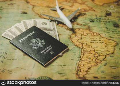 Top view of tourist planning props and travel accessories with American passport, airplane and US dollar banknote money on old grunge style map. Holiday and vacation. Tourism long weekend concept.