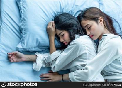 Top view of two Asian women sleeping on bed together. Lesbian lovers and couple concept. People and lifestyles theme.