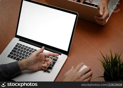 top view of two businessmen hand working with new modern computer laptop with blank screen and blank book as concept