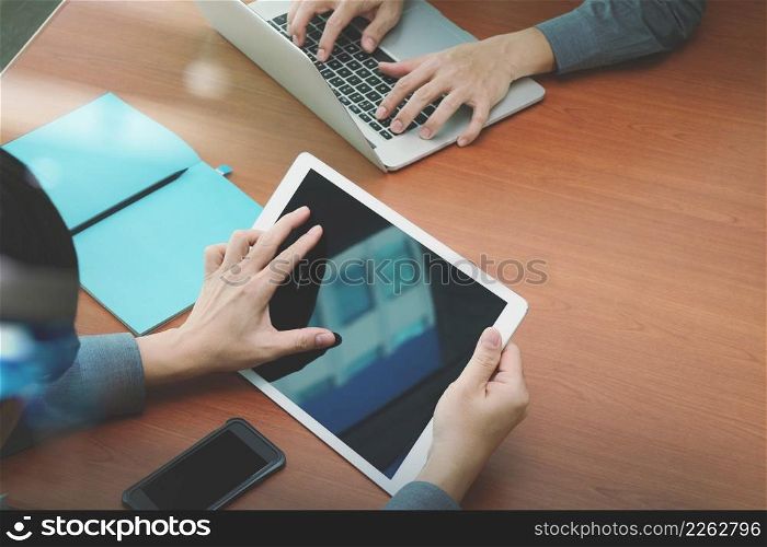 top view of two colleagues discussing data with blank screen new modern computer laptop and pro digital tablet on wooden desk as concept