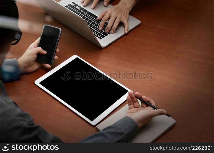 top view of two colleagues discussing data with new modern computer laptop and pro digital tablet with smart phone on wooden desk as concept