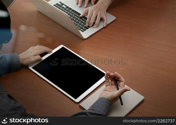 top view of two colleagues discussing data with new modern computer laptop and pro digital tablet on wooden desk as concept