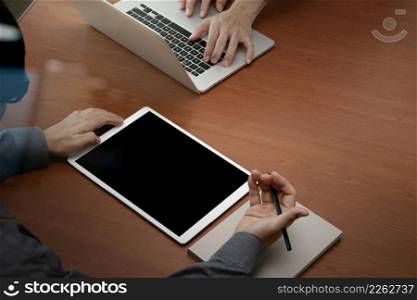 top view of two colleagues discussing data with new modern computer laptop and pro digital tablet on wooden desk as concept