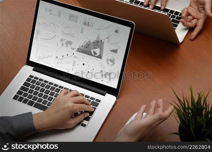 top view of two colleagues discussing data with new modern computer laptop with business strategy document and digital diagram as concept