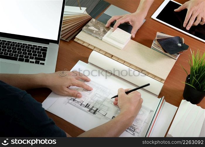 top view of two colleagues interior designers discussing data with blank screen new modern computer laptop and pro digital tablet with sample material on wooden desk as concept