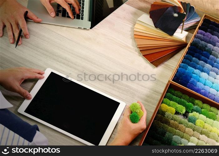 top view of two colleagues interior designers discussing data with digital tablet and new modern computer laptop with sample material on wooden desk as concept