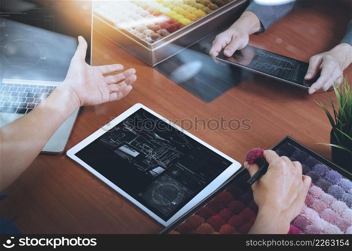 top view of two colleagues interior designers discussing data with new modern computer laptop and pro digital tablet with sample material on wooden desk as concept