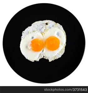 top view of two fry eggs on ceramic black plate isolated on white background