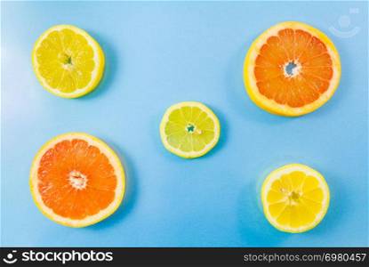 Top view of two grapefruit and three lemon slices on blue background. Minimalist picture style with some copy space for text