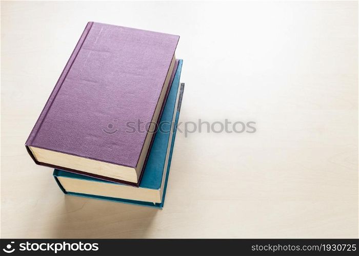 top view of two thick volumes of books on light brown wooden board
