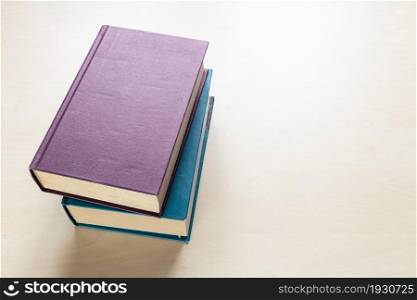 top view of two thick volumes of books on light brown wooden board