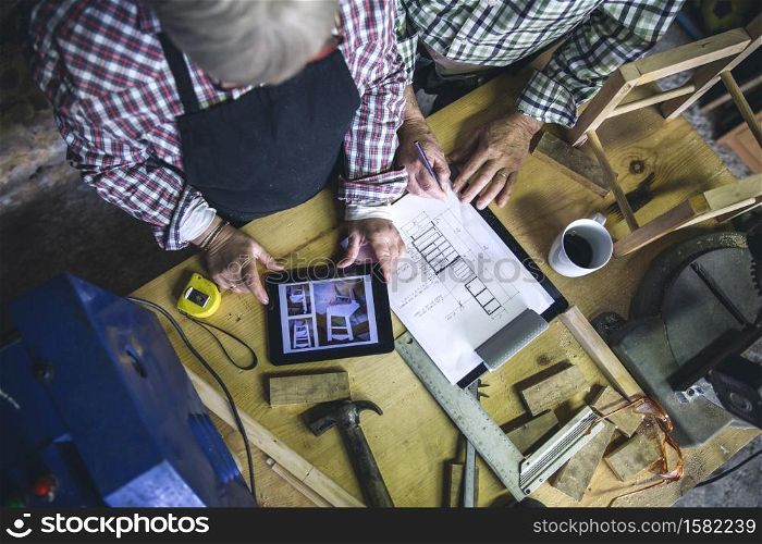 Top view of unrecognizable senior couple working in a carpentry workshop. Senior couple in a carpentry