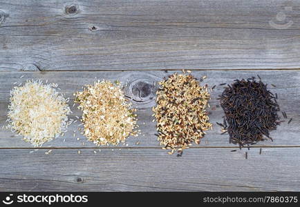 Top view of various rice types each within an individual pile on rustic wood