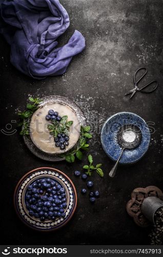Top view of vegan no bake blueberry cake on dark rustic kitchen table background with fresh berries, side view. Healthy food