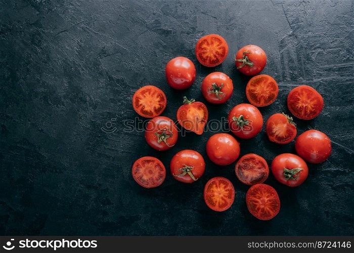 Top view of very ripe tomatoes and slices on dark background with free space. Organic fresh vegetables containing vitamins. Healthy eating