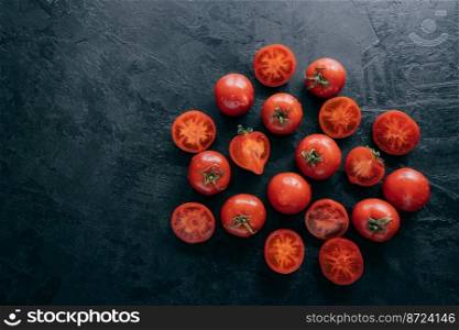 Top view of very ripe tomatoes and slices on dark background with free space. Organic fresh vegetables containing vitamins. Healthy eating