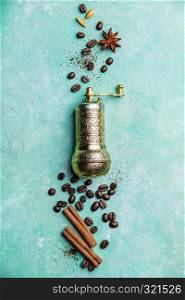 Top view of vintage manual coffee grinder, coffee beans and spices, space for text, blue background