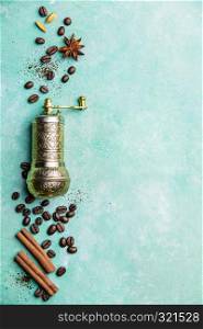 Top view of vintage manual coffee grinder, coffee beans and spices, space for text, blue background