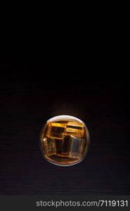 top view of whiskey in glass with ice on black background