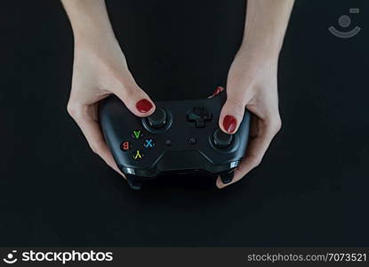 Top view of woman hands with red nail polish on fingers holding a logo free modern gaming controller for playing digital video games isolated on black for fun leisure entertainment.. Top view of woman hands with red nail polish on fingers holding a logo free modern gaming controller for playing digital video games isolated on black for fun leisure entertainment