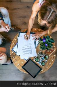 Top view of woman signing a document at an informal work meeting. Top view of woman signing a document