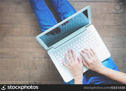 Top view of woman using laptop sitting on wooden floor, Lifestyle concept with copy space