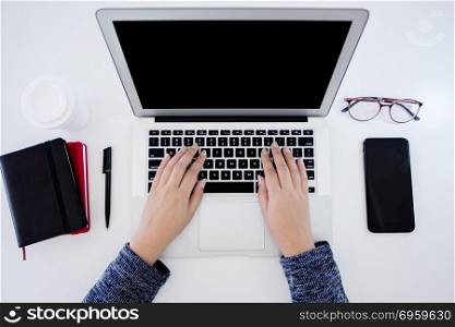 top view of woman using laptop with notebook and smartphone gadget. top view of woman using laptop with notebook and smartphone gadg