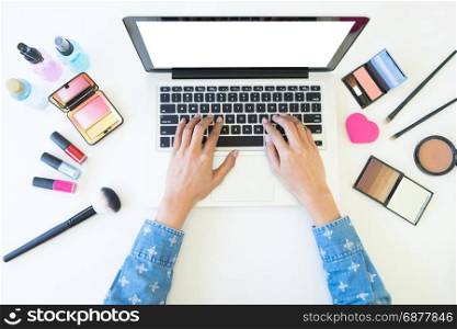 top view of women using laptop for searching cosmetic information for makeup, beauty concept