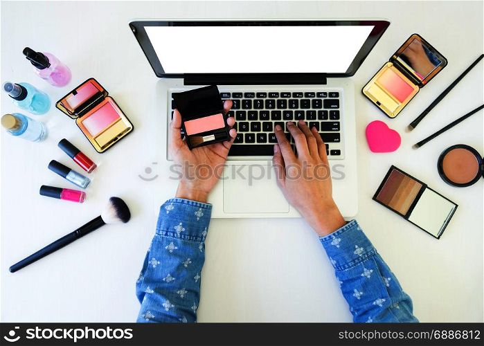 top view of women using laptop for searching cosmetic information for makeup, beauty concept