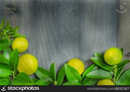 top view of wooden background with fresh lime and green leaves