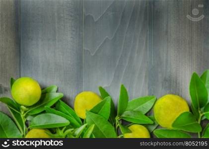 top view of wooden background with fresh lime and green leaves