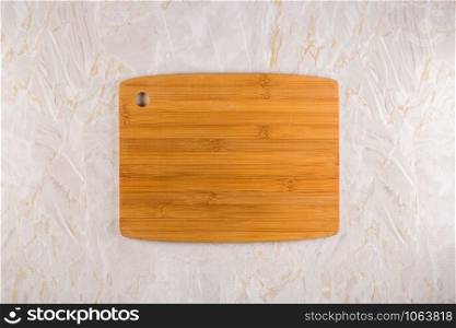 Top view of wooden cutting board on a gray marble background with space for text.