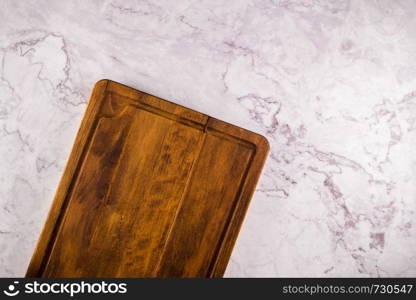 Top view of wooden cutting board on a gray marble background with space for text.