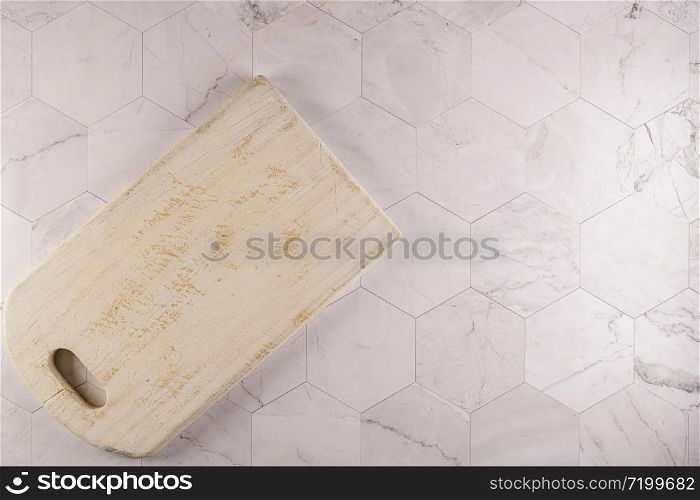 Top view of wooden cutting board on modern hexagonal pattern marble stone countertop.