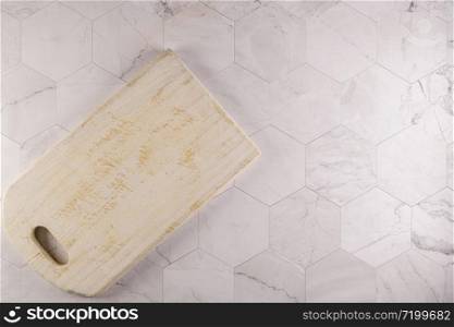 Top view of wooden cutting board on modern hexagonal pattern marble stone countertop.