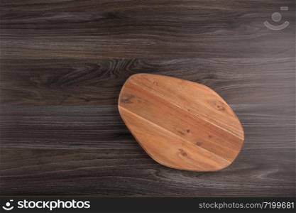 Top view of wooden cutting board on old dark wood countertop.