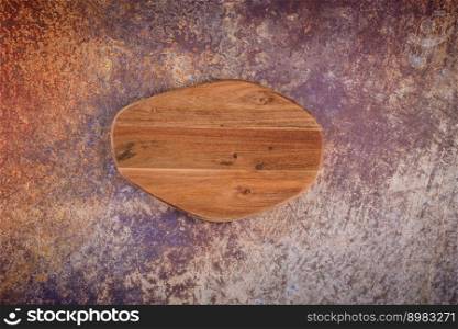 Top view of wooden cutting board on old rusty metal countertop.