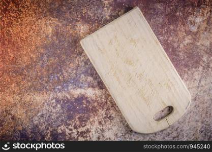 Top view of wooden cutting board on old rusty metal countertop.