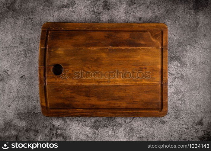 Top view of wooden cutting board on old stone countertop.