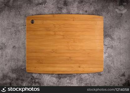 Top view of wooden cutting board on old stone countertop.