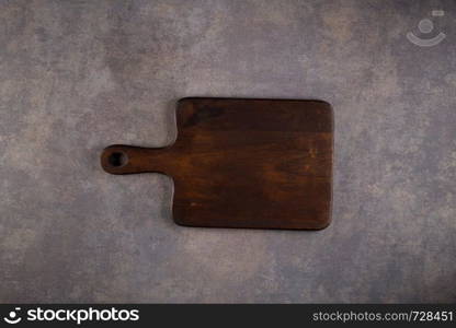 Top view of wooden cutting board on old stone countertop.