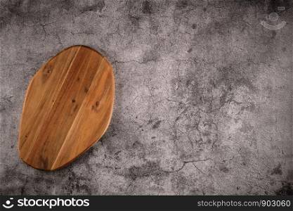 Top view of wooden cutting board on old stone countertop.