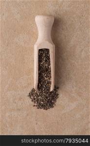 Top view of wooden scoop with chia seeds against beige vinyl background.