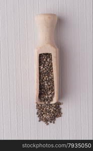 Top view of wooden scoop with chia seeds against white vinyl background.