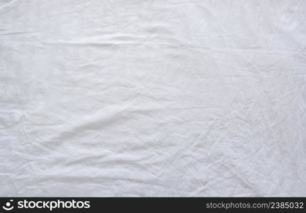 Top view of wrinkles on an unmade bed sheet after waking up in the morning.
