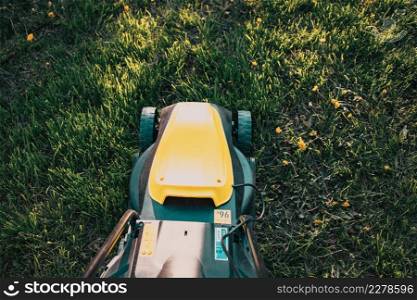 top view of yellow lawn mower in green grass