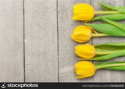 Top view of yellow tulips over wooden table