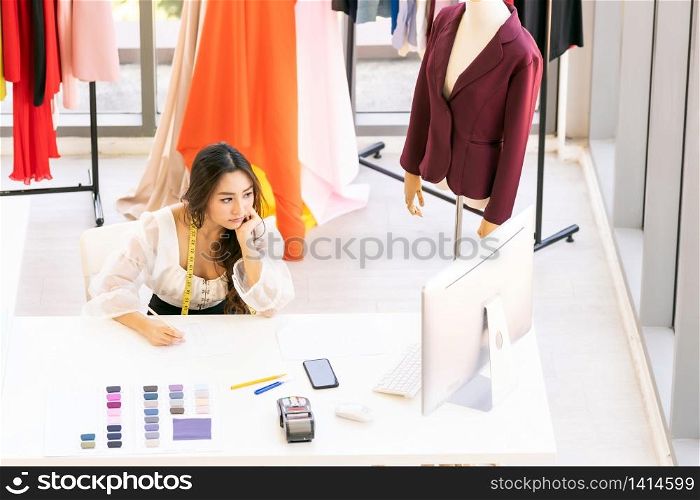 Top view of young adult asian fashion designer drawing and sketching her work at home as atelier studio with colour palette. Using for entrepreneur small business startup concept.